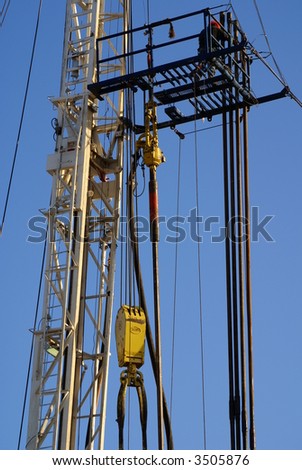 Roustabout works on high platform of oil drilling rig, Kern County, California