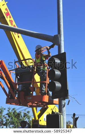 BAKERSFIELD, CA - AUG 12: Electricians completely replace traffic signals, poles and mast arms at a major intersection on August 12, 2010, at Bakersfield, California. Mast arm is bolted to the pole.