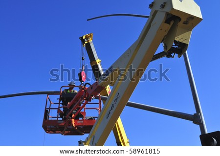 BAKERSFIELD, CA - AUG 12: Electricians completely replace traffic signals, poles and mast arms at a major intersection on August 12, 2010, at Bakersfield, California. Mast arm is positioned.