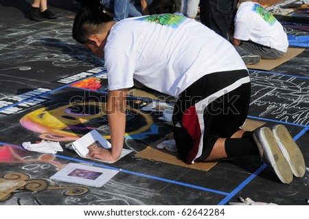BAKERSFIELD, CA - OCT 9: Local student applies chalk to asphalt for the Via Arte Italian Street Painting Festival on October 9, 2010, at Bakersfield, California
