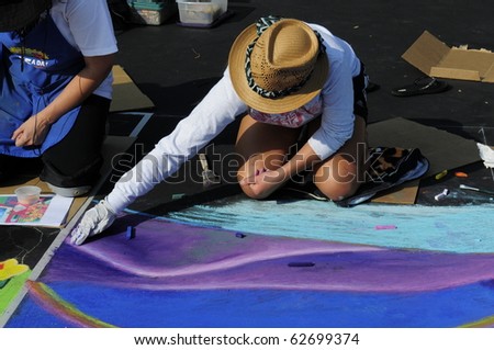 BAKERSFIELD, CA - OCT 9: Local student applies chalk to asphalt for the Via Arte Italian Street Painting Festival on October 9, 2010, in Bakersfield, California
