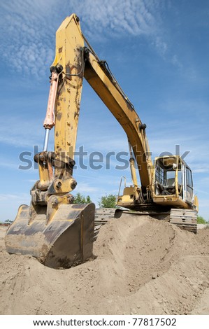 Heavy equipment prepares construction job site: Articulated boom and digging bucket
