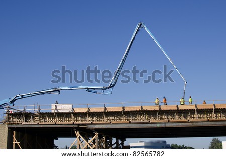 Concrete is pumped into wooden forms with an articulated boom for a bridge construction project