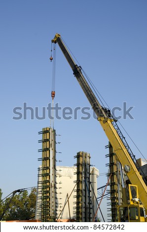 Crane is used to lift concrete form for columns into place on a construction job site