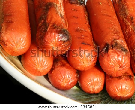 Juicy hot dogs with grill marks in a dish after being taken off the barbecue