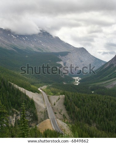 Photo of a road leading into the mountains.  Displays roadtrip and travel by automobile concepts.