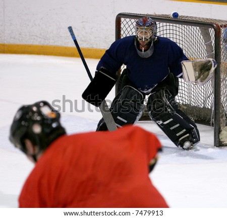 Ice hockey goalie prepares to attempt to defend his goa against an opposing player