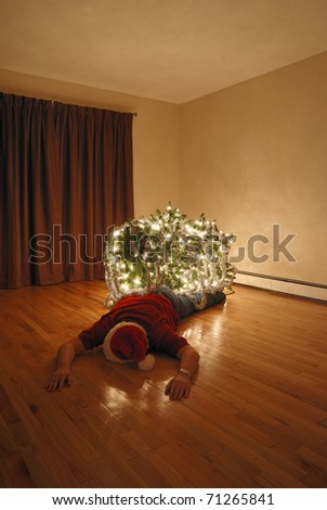 A Christmas tree lays on top of an unconscious man.