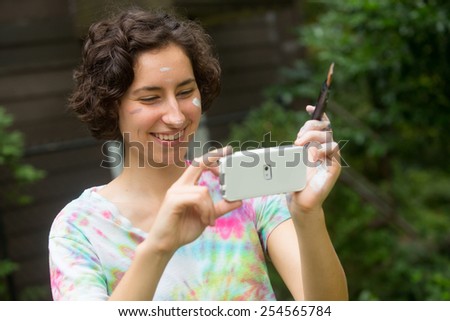 young woman painting on canvas outside