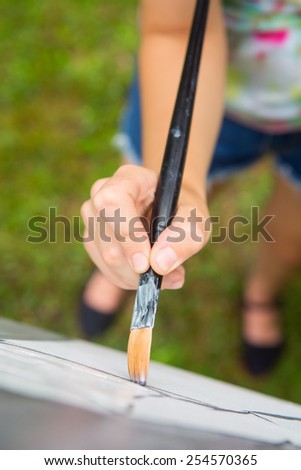 young caucasian woman painting on canvas outside