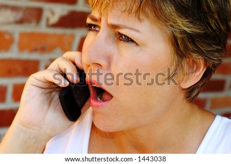 A woman reacting with surprise to a cell phone call.
