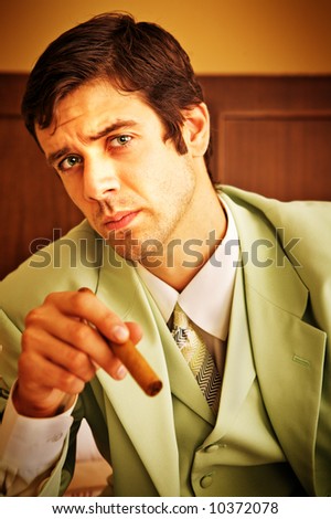 A sad business man in a room, holding a cigar.