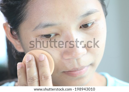 woman applying make up by press face powder