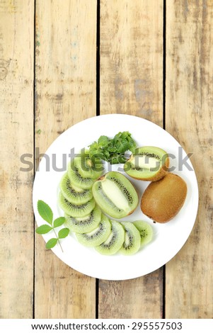 Close up kiwi fruit slice on white dish, Plank wood background.View from above.