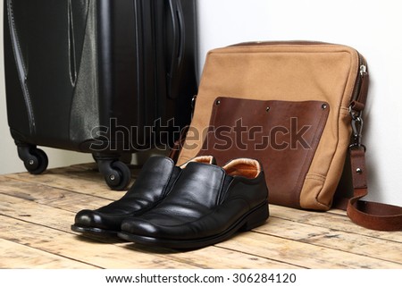 Black leather shoes and  luggage travel bag on the wooden table