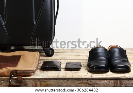 Black leather shoes, wallet,mobile smart phone and  luggage travel bag on the wooden table