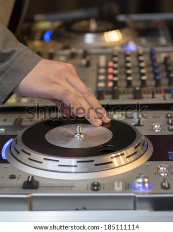 Hand of a DJ rotating his equipment to produce effects. DJ professional equipment operated by a skillful Disc Jockey