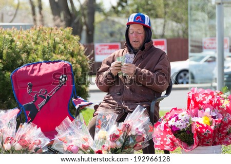 TORONTO,CANADA-MAY 11, 2014: Senior citizen selling flowers and counting money in the streets of Toronto during Mothers Day. CanadaÃ¢Â?Â?s elderly poverty rate rose between the mid-1990s and late 2000s.