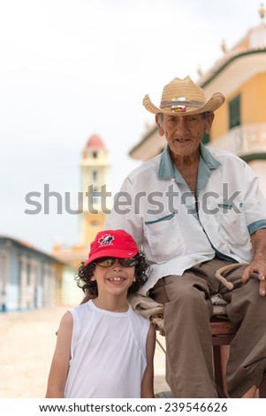 TRINIDAD,CUBA-JULY 22,2014: Senior Cuban citizen in a horse drawn carriage and charging tourist for photos. Trinidad is the eight village founded by Spanish colonizers and a UNESCO world heritage site