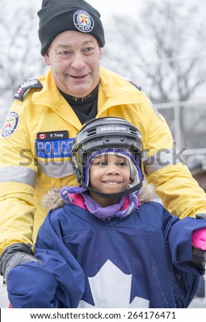 TORONTO,CANADA-JANUARY 3,2015: Toronto Police members partake in the official opening of the Regent Park ice rink; they served the community helping children in learning skating skills
