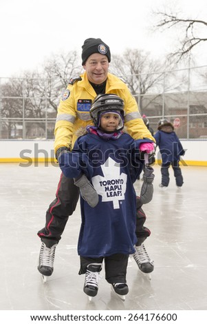 TORONTO,CANADA-JANUARY 3,2015:Toronto Police members partake in the official opening of the Regent Park ice rink; they served the community helping children in learning skating skills