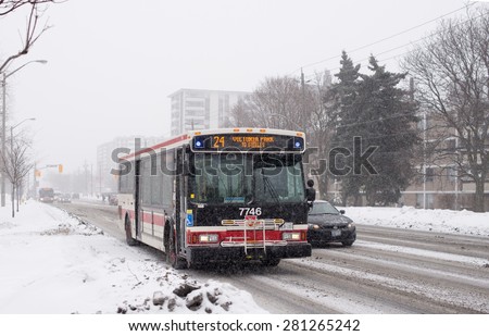 TORONTO,CANADA-FEBRUARY 20,2015: TTC bus and car moving on the street with snow covered in winter morning, everyday scene of a Winter day in the city. TTC is a public transportation company.
