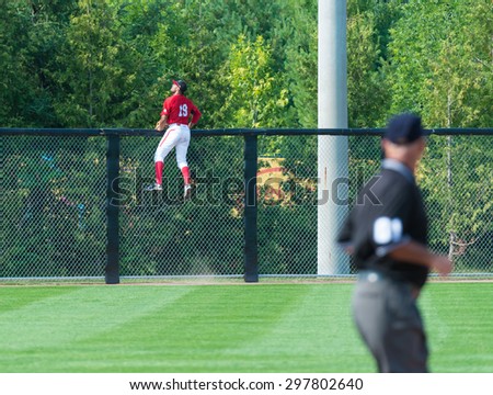 TORONTO,CANADA-JULY 12,2015: Toronto Pan American Games 2015, Baseball tournament: Tyson Gillies goes over a fence trying to catch a home run hit by Colombian team  Case number - 01953074