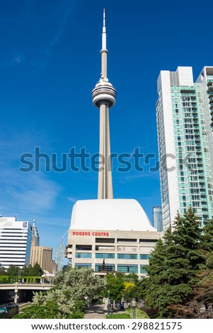 TORONTO,CANADA-JUNE 15,2015: Rogers Centre sports stadium with the CN Tower and skyscrapers against blue sky. Rogers Centre is a multi-purpose stadium situated just southwest of the CN Tower.
