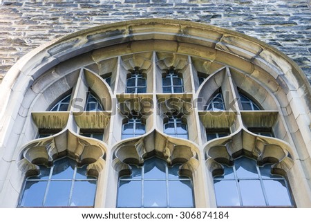 Low angle elevation view of the University of Toronto building. The arch shaped structure has many smaller windows. The University of Toronto is a public research university in Toronto