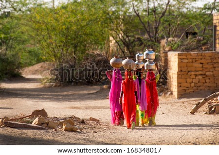 Water carries heading home, desert village near Jailsalmer, Rajasthan, India.