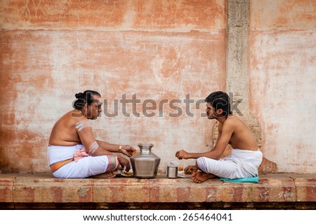 THANJAVUR, INDIA - JAN 12; Two Hindu priests eat lunch at Brihadisvara Temple on Jan 12 2014 in Thanjavur, Tamil Nadu, India.