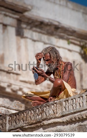 UDAIPUR, INDIA - FEBRUARY 15, 2009: A Hindu sadhu holyman applying face paint outside a temple in Udaipur, Rajasthan, India.