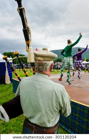 LOCHEARNHEAD, SCOTLAND- JULY, 24,2010: A lone bagpiper plays for dancers doing the sword dance at a Scottish Highland games event on July, 24, 2010 in Lochearnhead..