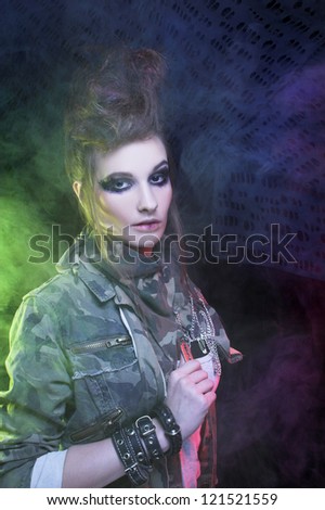 Punk. Young woman with smokey eyes and with artistic hairstyle posing with smoke
