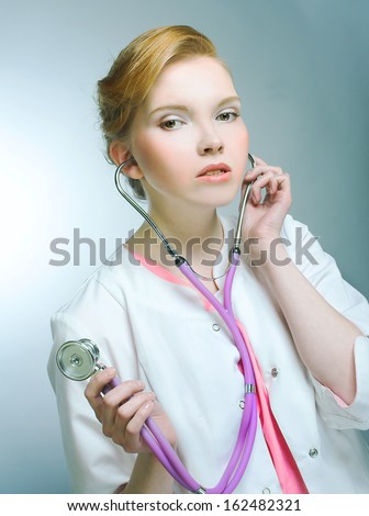 Portrait of young woman in doctor\'s smock and with stethoscope