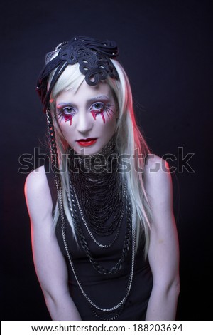 Young woman in black dress and with bloody tears.