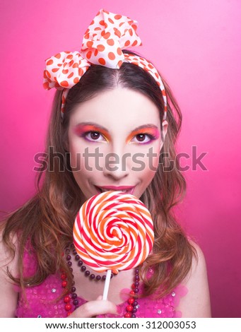 Portrait of charming girl in summer dress with creative make-up and with lollipop.