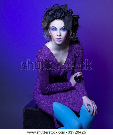 Portrait of young stylish woman in violet dress and little black hat