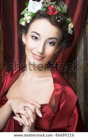 Portrait of young lady in red dress with flowers in her hair.