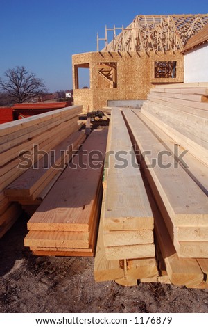 Lumber with a home under construction in the background.