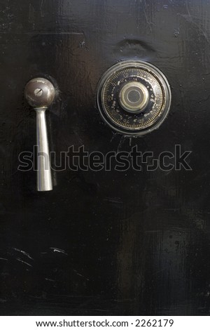 A close-up of an antique safe door including the combination lock.