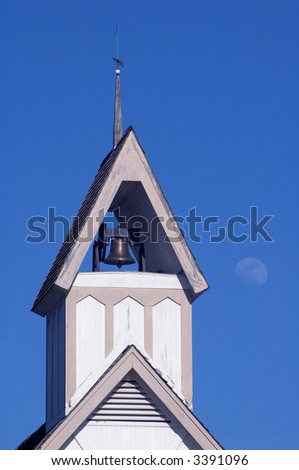 Close-up of the steeple of a country church with the moon in the background.