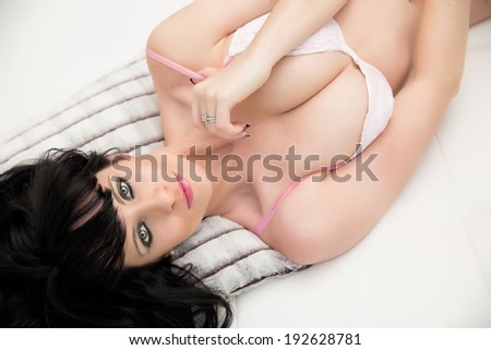 Beautiful young woman wearing white lingerie on white couch