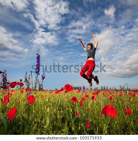 Happiness girl in jump among red poppy