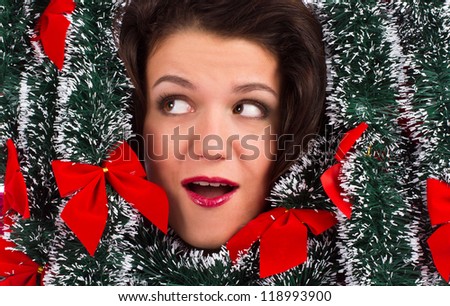 Face of beautiful smiling woman looking sideways up with christmas tinsel