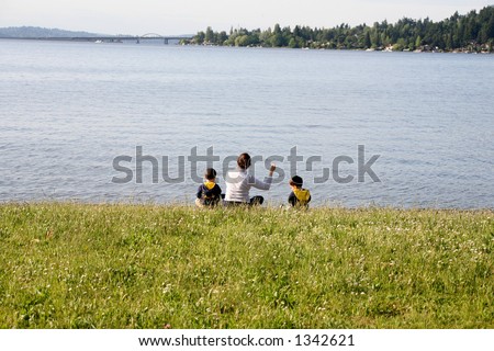 A mother and her two sons throwing stones into the lake
