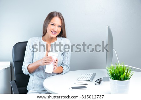 Portrait of smiling modern business woman in office working and drinking coffee