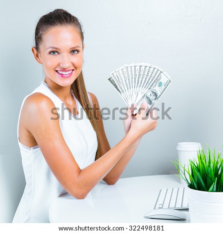 smiling woman holding money and siting in her office. successful business woman with money.