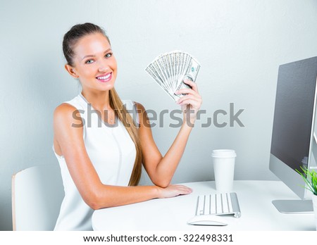 smiling woman holding money and siting in her office. successful business woman with money.