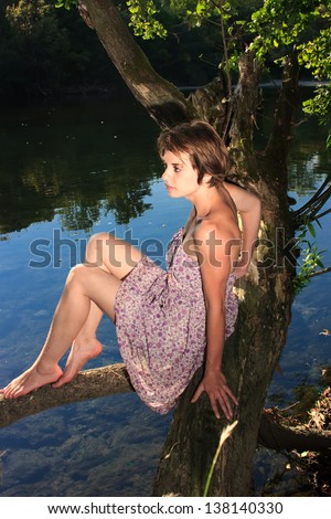 Beautiful young woman in dress sitting by the river